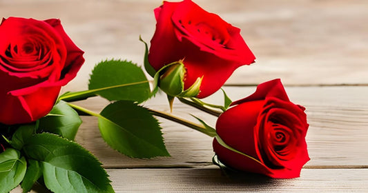 Three red roses on wood table.