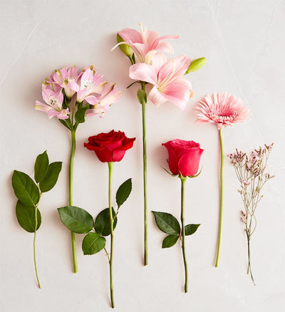 Arrangement of flowers including pink lilies, red roses, and green leaves on a light background Arrangement of flowers including pink lilies, red roses, and green leaves on a light background