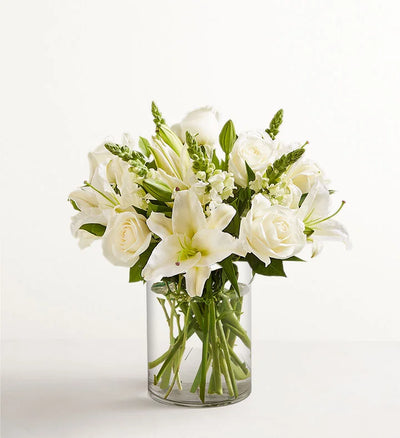 Classic All White Arrangement Bouquet of white flowers in a clear vase on a white background Classic All White Arrangement Bouquet of white flowers in a clear vase on a white background