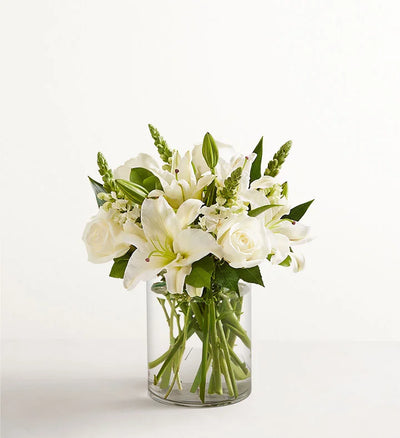 Classic All White Arrangement, Bouquet of white flowers in a clear glass vase on a white background Classic All White Arrangement, Bouquet of white flowers in a clear glass vase on a white background