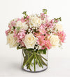 Bouquet of pink and white flowers in a clear vase on a white background