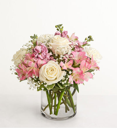 Bouquet of pink and white flowers in a clear vase on a white background Bouquet of pink and white flowers in a clear vase on a white background