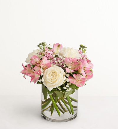 Bouquet of pink and white flowers in a clear vase on a white background Bouquet of pink and white flowers in a clear vase on a white background