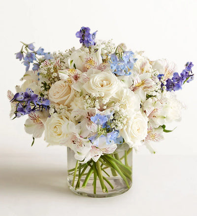 Wonderful Wishes Bouquet of white and purple flowers in a clear vase on a light background Wonderful Wishes Bouquet of white and purple flowers in a clear vase on a light background