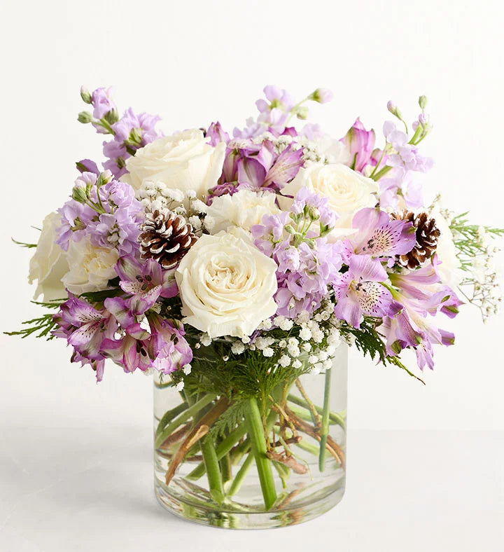 Lovely Lavender Medley for Winter Bouquet of white and purple flowers in a clear vase on a white background