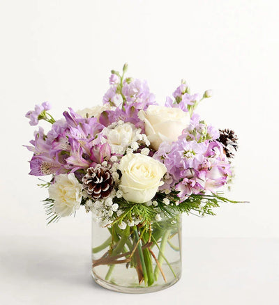 Lovely Lavender Medley for Winter Bouquet of flowers with white and purple flowers in a clear vase on a white background Lovely Lavender Medley for Winter Bouquet of flowers with white and purple flowers in a clear vase on a white background