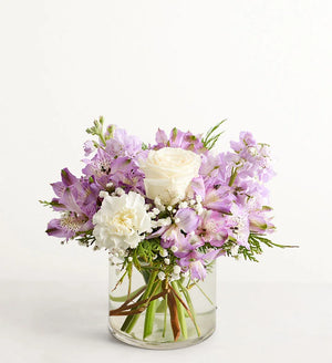 Lovely Lavender Medley for Winter Bouquet of purple and white flowers in a clear vase on a white background