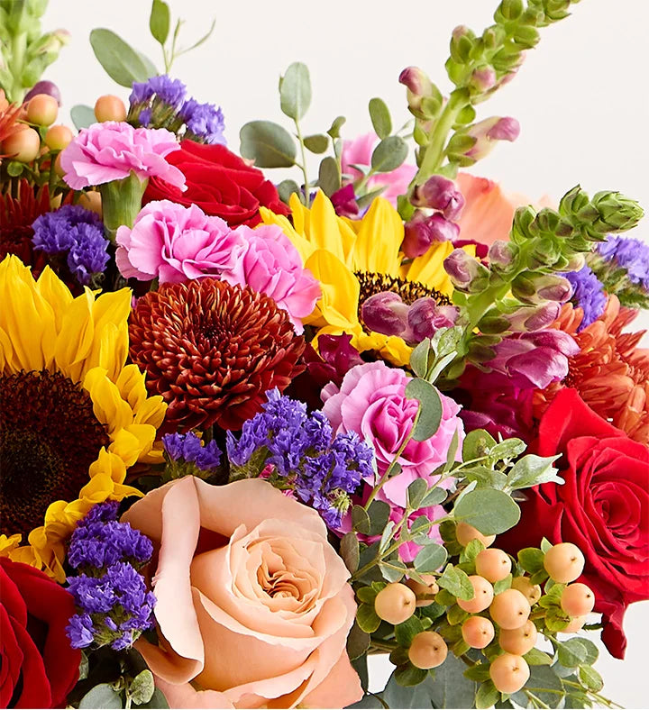 Bouquet of colorful flowers including sunflowers, roses, and berries on a white background