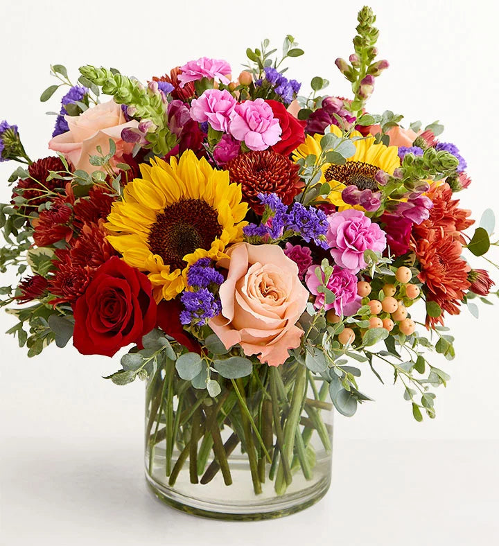 Harvest Melody Bouquet Colorful bouquet of flowers in a clear vase on a white background