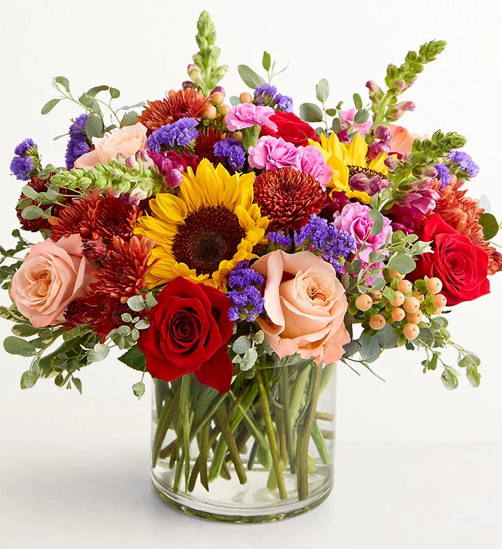 Harvest Melody Bouquet Colorful bouquet of flowers in a clear vase on a white background