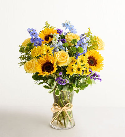 Bouquet of sunflowers and yellow roses in a clear vase on a white background Bouquet of sunflowers and yellow roses in a clear vase on a white background