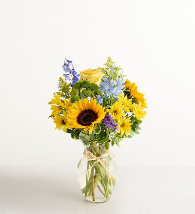 Bouquet of sunflowers, roses, and other flowers in a glass vase on a white background Bouquet of sunflowers, roses, and other flowers in a glass vase on a white background