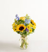 Bouquet of sunflowers, roses, and other flowers in a glass vase on a white background