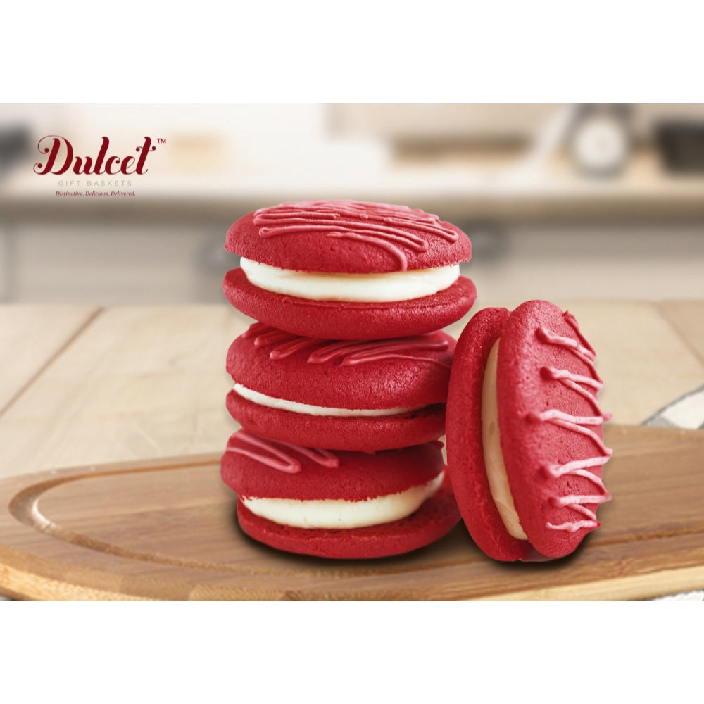 Red cookies with white filling on a wooden board, featuring the Dulced brand.