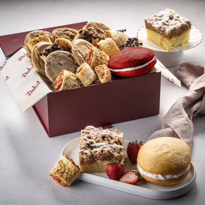 Assorted cookies and pastries in a box with a red lid on a gray surface. Assorted cookies and pastries in a box with a red lid on a gray surface.