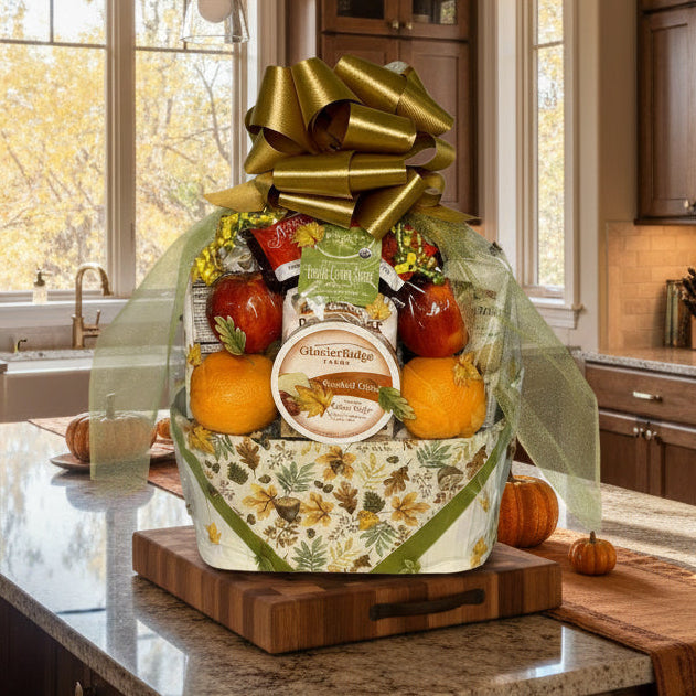 Gift basket with autumn-themed design, including pumpkins and a large gold bow in kitchen..