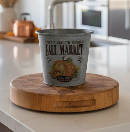 Metal bucket with 'Fall Market' text and pumpkin illustration in a kitchen.