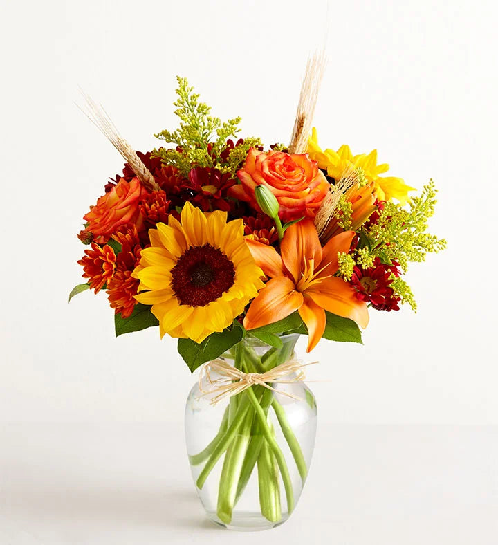 Bouquet of autumn flowers in a clear vase on a white background