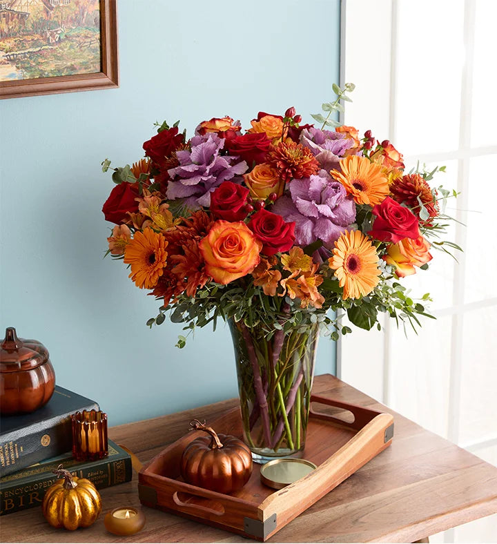 Garden of Grandeur for Fall Colorful bouquet of flowers in a glass vase on a wooden tray with pumpkins and candles.