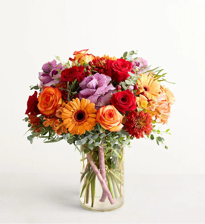 Garden of Grandeur for Fall Bouquet of colorful flowers in a clear vase on a light background