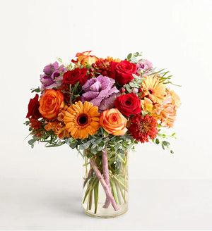 Garden of Grandeur for Fall Bouquet of colorful flowers in a clear vase on a light background