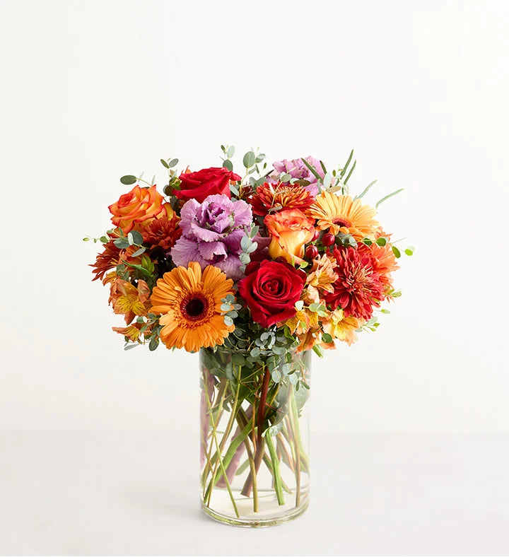 Garden of Grandeur for Fall Bouquet of colorful flowers in a clear vase on a light background