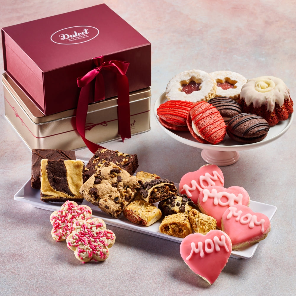 Assorted cookies including 'Mom' cookies, a red ribbon box, and a platter of cookies on a light background.
