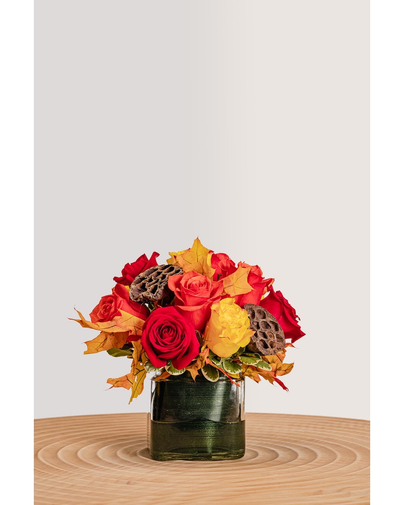 Fall colored roses, with fall colored greenery in a vase.