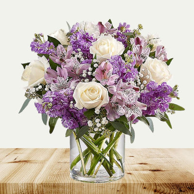 White roses with pink alstroemeria, purple stock, white carnations and baby's breath arranged in a clear glass vase. White roses with pink alstroemeria, purple stock, white carnations and baby's breath arranged in a clear glass vase.