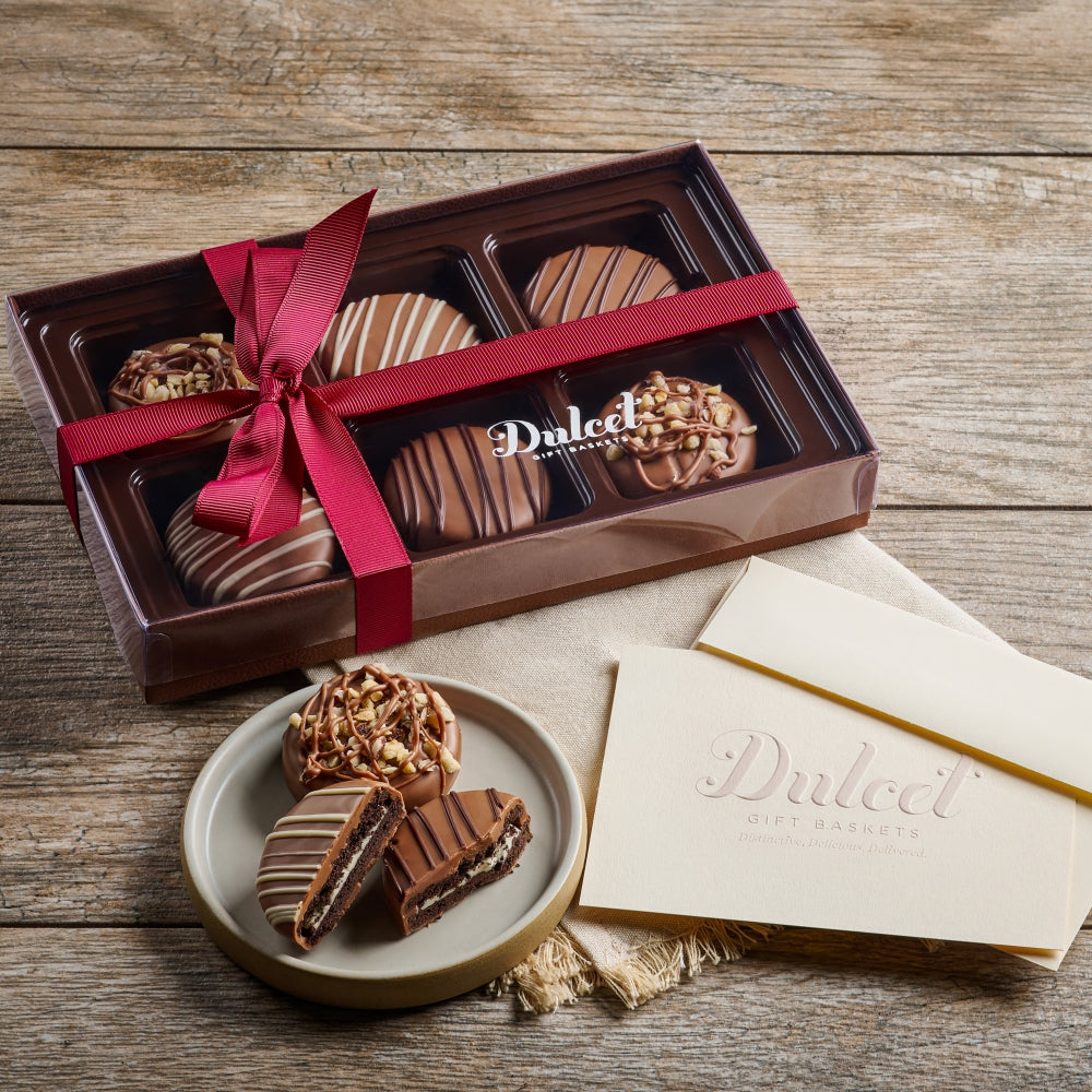 Chocolate assortment in a box with a red ribbon on a wooden surface, featuring the brand 'Dulce'.