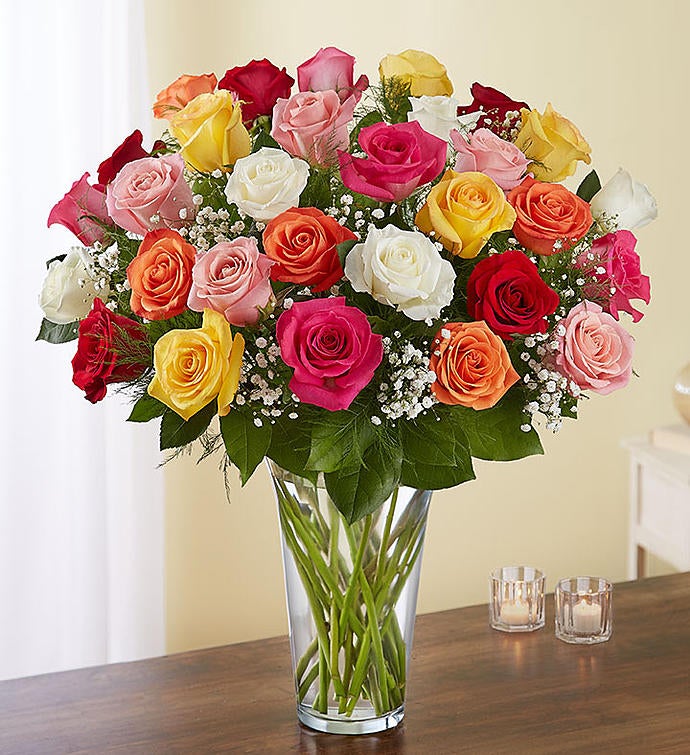 36 Stems Assorted Exquisite bouquet of multicolored long-stem roses arranged in a tall clear glass vase, featuring a vibrant mix of red, pink, yellow, and orange roses with baby’s breath and greenery, ideal for expressing grand emotions.