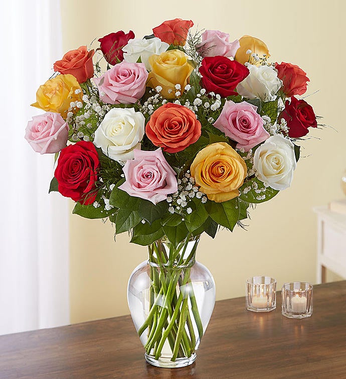 24 Stems Assorted Exquisite bouquet of multicolored long-stem roses arranged in a tall clear glass vase, featuring a vibrant mix of red, pink, yellow, and orange roses with baby’s breath and greenery, ideal for expressing grand emotions.