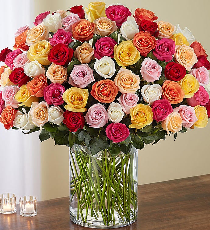 Spectacular arrangement of 100 long-stem multicolored roses in a clear glass vase, featuring an array of vibrant red, pink, yellow, and orange roses, perfect for expressing grand emotions and making a significant impact.