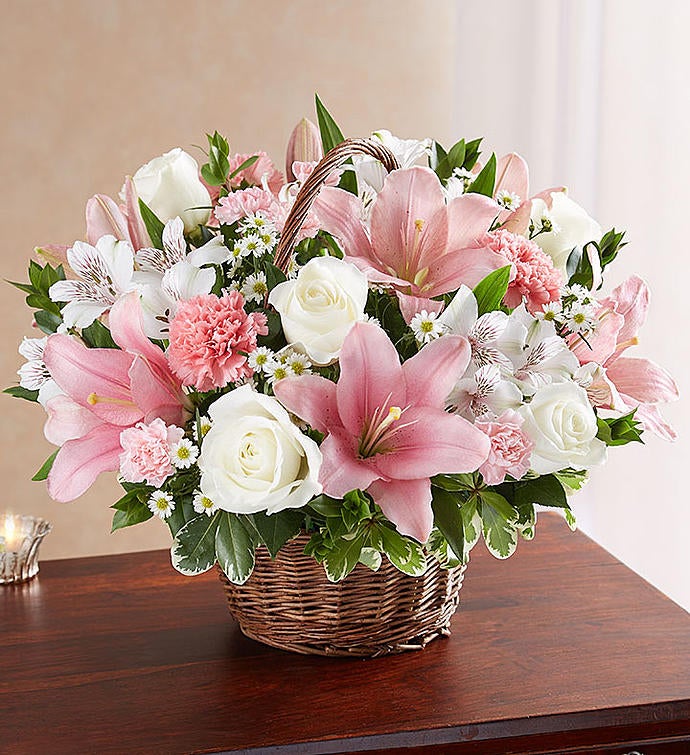 Large Elegant pink and white floral arrangement in a wicker basket, featuring pink Asiatic lilies, carnations, and mini carnations, complemented by white roses, alstroemeria, monte casino, and lush greenery, ideal for expressing sympathy and care.