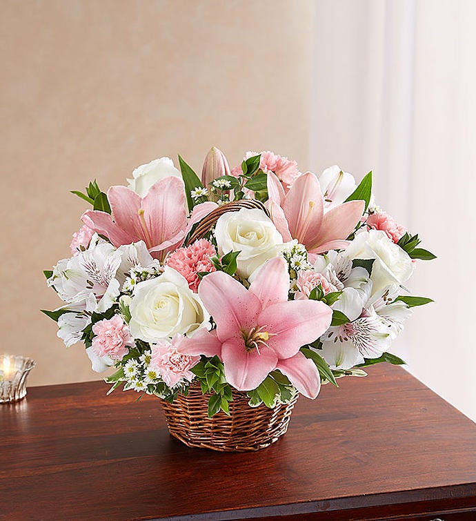 Medium Elegant pink and white floral arrangement in a wicker basket, featuring pink Asiatic lilies, carnations, and mini carnations, complemented by white roses, alstroemeria, monte casino, and lush greenery, ideal for expressing sympathy and care.