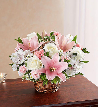 Medium Elegant pink and white floral arrangement in a wicker basket, featuring pink Asiatic lilies, carnations, and mini carnations, complemented by white roses, alstroemeria, monte casino, and lush greenery, ideal for expressing sympathy and care. Medium Elegant pink and white floral arrangement in a wicker basket, featuring pink Asiatic lilies, carnations, and mini carnations, complemented by white roses, alstroemeria, monte casino, and lush greenery, ideal for expressing sympathy and care.