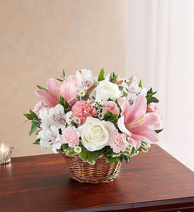 Small Elegant pink and white floral arrangement in a wicker basket, featuring pink Asiatic lilies, carnations, and mini carnations, complemented by white roses, alstroemeria, monte casino, and lush greenery, ideal for expressing sympathy and care. Small Elegant pink and white floral arrangement in a wicker basket, featuring pink Asiatic lilies, carnations, and mini carnations, complemented by white roses, alstroemeria, monte casino, and lush greenery, ideal for expressing sympathy and care.