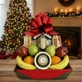Fruit basket with a large red bow in front of a Christmas tree and fireplace.