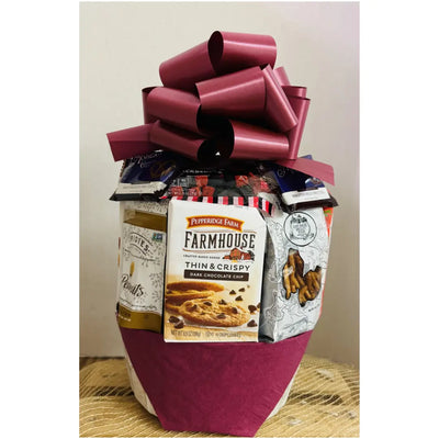 Gift basket with a large red bow containing snacks and cookies on a neutral background Gift basket with a large red bow containing snacks and cookies on a neutral background